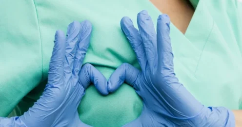 Doctor with hand shaped heart over chest