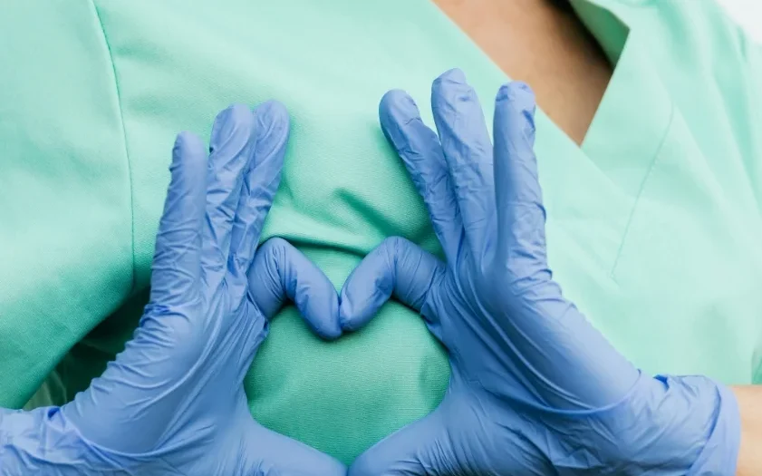 Doctor with hand shaped heart over chest